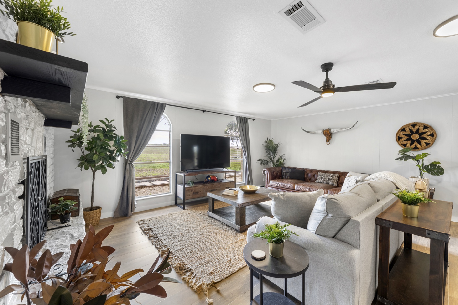 Cozy den with brown leather and grey sofas, stone fireplace