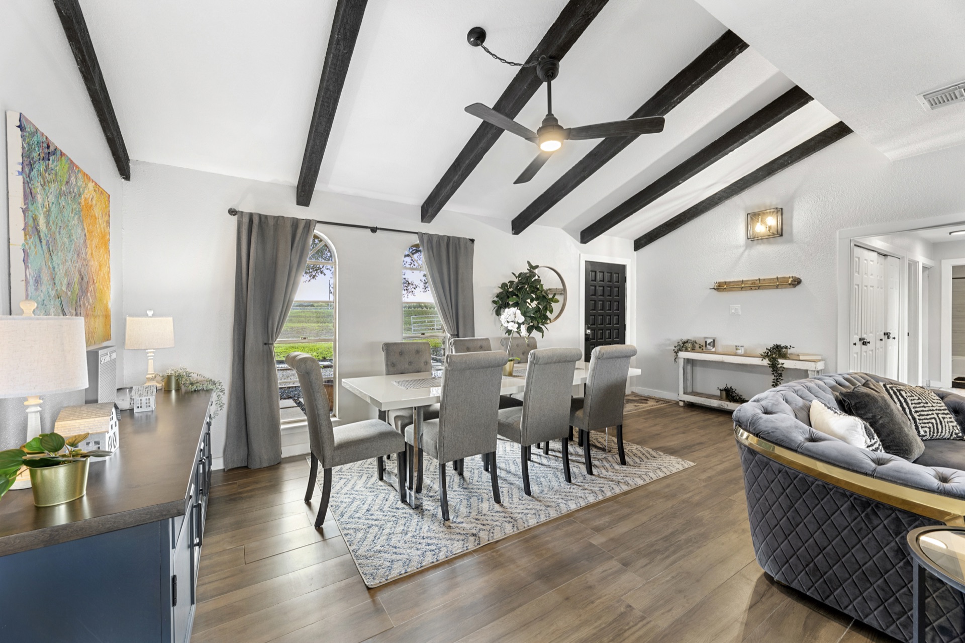 Dining area with 8-seat table, vaulted ceiling, and arched windows