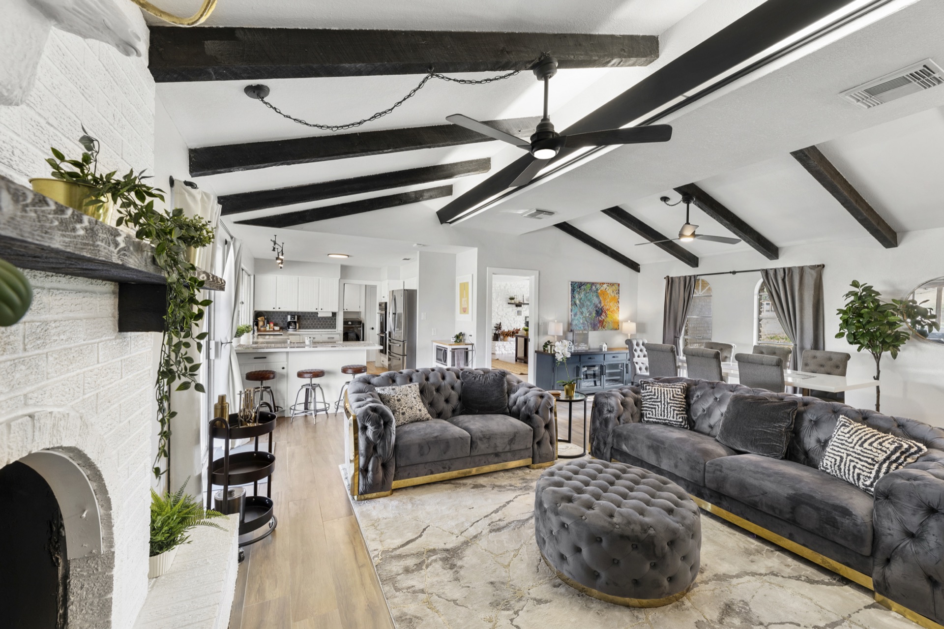 Open-plan living area with grey tufted sofas and exposed dark beams