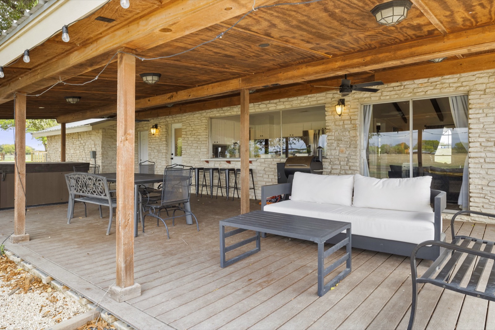 Covered patio with outdoor sofa, dining area, and string lights