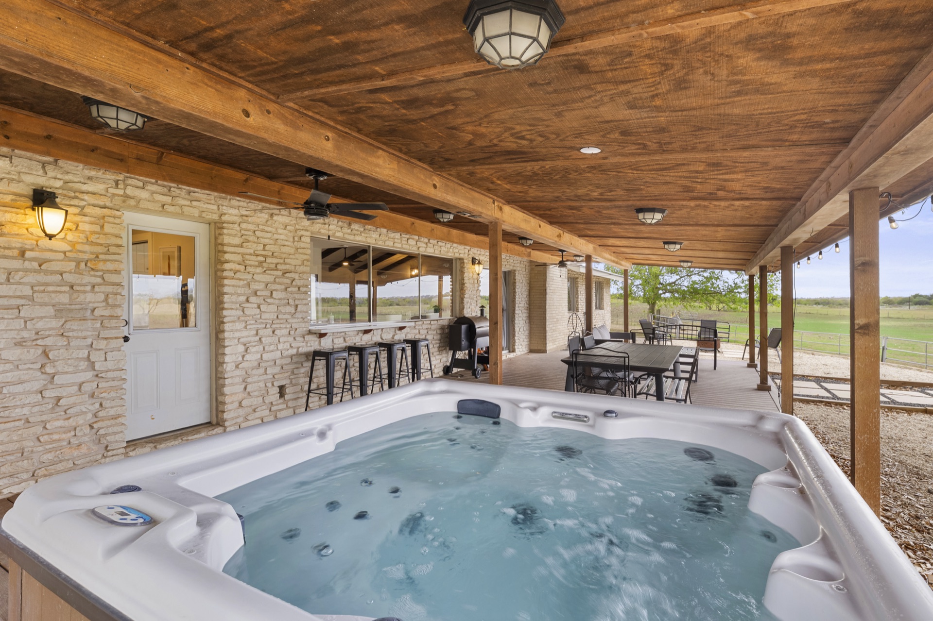 Hot tub under covered patio with bar area and farm views